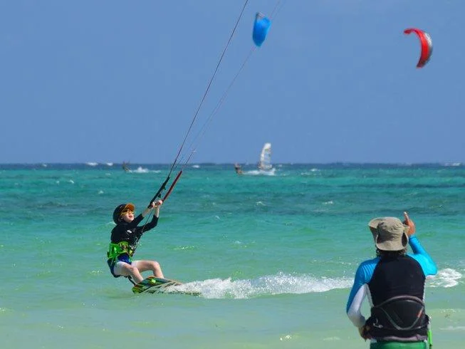 Beginner learning kitesurfing with an instructor in shallow water at Diani Beach